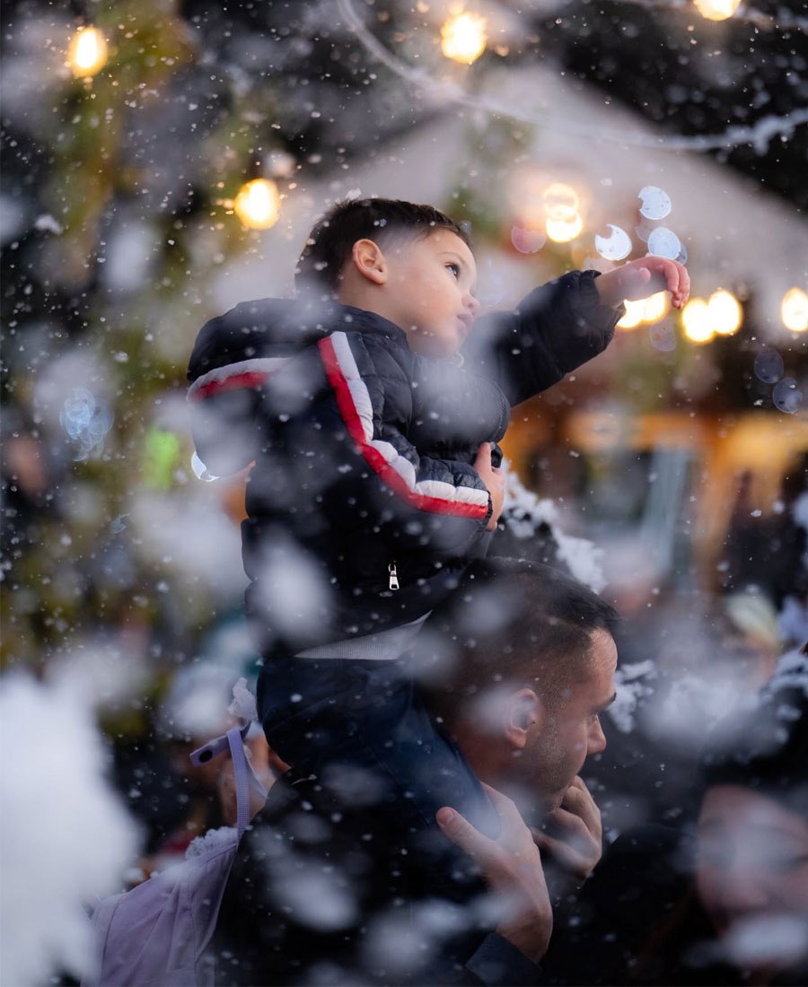 bambino sulle spalle di padre sotto la neve